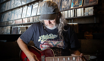 A person playing a guitar inside Grady's Green Room.
