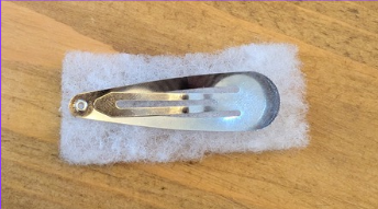A hair clip placed over a piece of foam ready to cut around