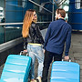 cute-couple-is-walking-with-suitcases-outside-airport-she-has-long-hair-glasses-yellow-swe