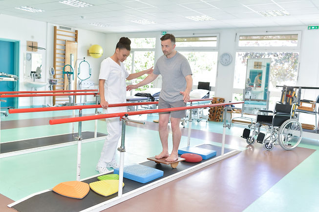 Man balancing with physiotherapist.jpg