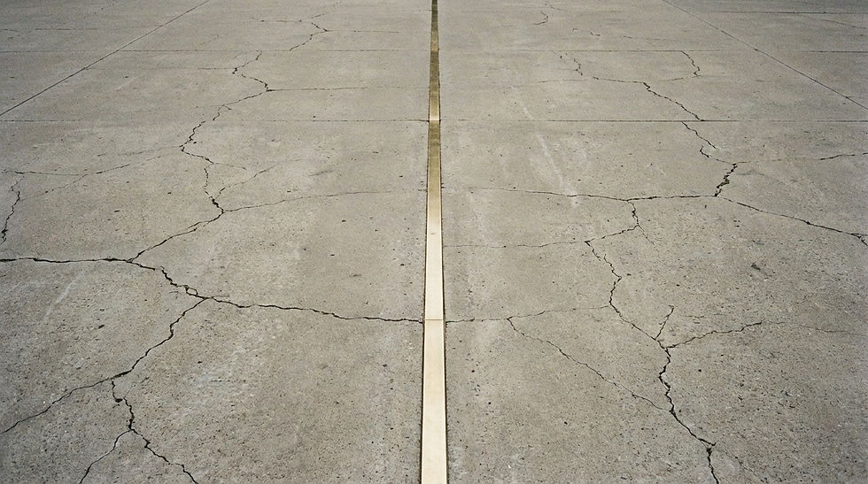 A cracked concrete surface features a straight, light-colored line running through the center. The setting appears barren and desolate.