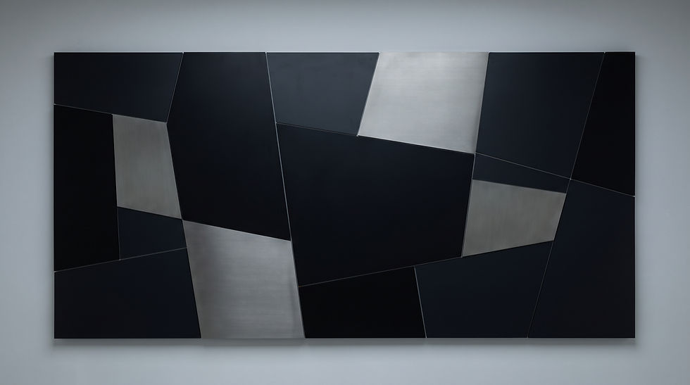 Abstract geometric wall art with black and silver angular panels on a gray wall, creating a sleek, minimalist look.