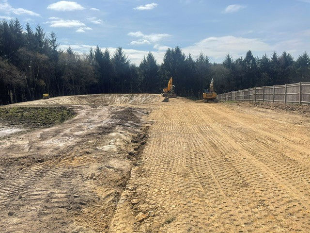 Construction site with graded dirt and heavy equipment in background