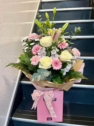 Hand tied bouquet of pink gerberas and white roses in a pink gift box