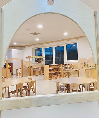 Spacious kindergarten classroom with wooden furniture, toys, and activities