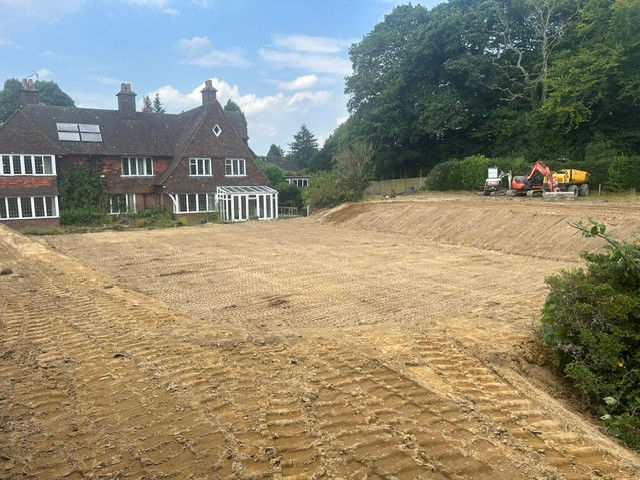 Freshly graded dirt lot beside a red-brick suburban house
