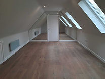 Spacious attic bedroom with wooden flooring.