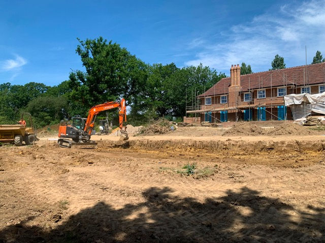Excavated gravel drainage trench on a construction site with heavy equipment nearby