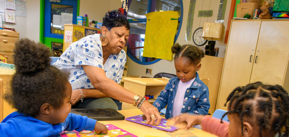 A teacher helps students with their puzzles.