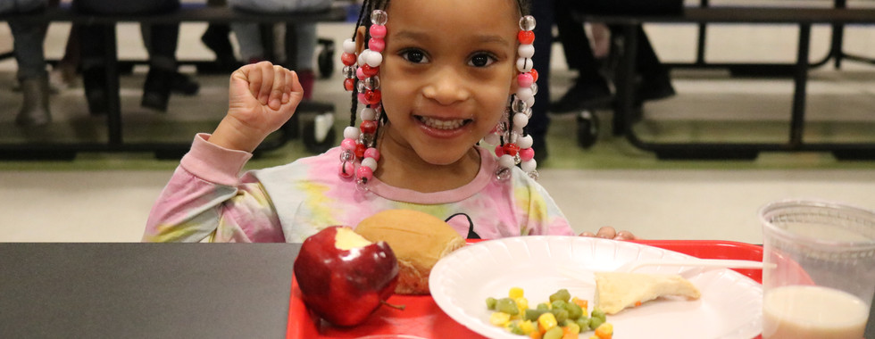 A child eats lunch in a lunch room.
