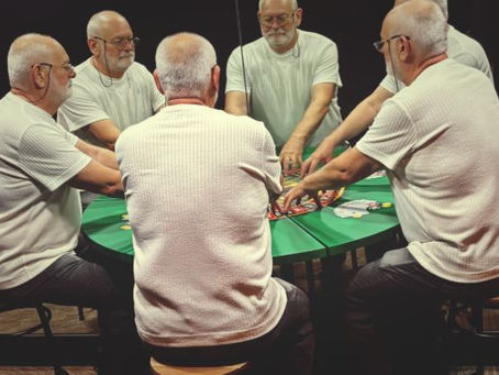 homem sentado com mãos na mesa com vários reflexos seu em espelhos