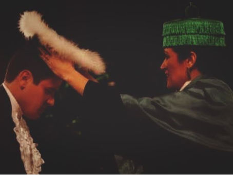 em uma formatura, a professsora colocando o chapéu no aluno formado