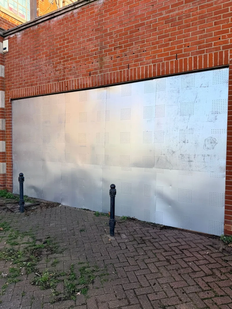 Perforated steel security screens installed on vacant commercial property in the UK