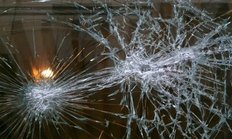 Broken window glass on an abandoned commercial property, highlighting vulnerability to crime and trespassing