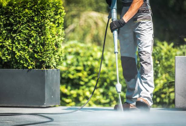 Worker pressure washing a concrete patio floor outdoors