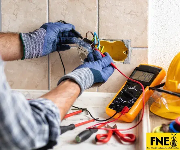 A professional electrician working on an open residential electrical panel, using a digital multimeter tool to test wiring and components.