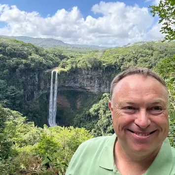 Stefan at a scenic waterfall surrounded by lush tropical forest