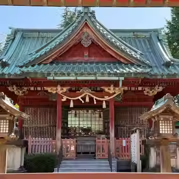 A vermilion shrine building with a green roof and ornate carved details in Kanazawa.