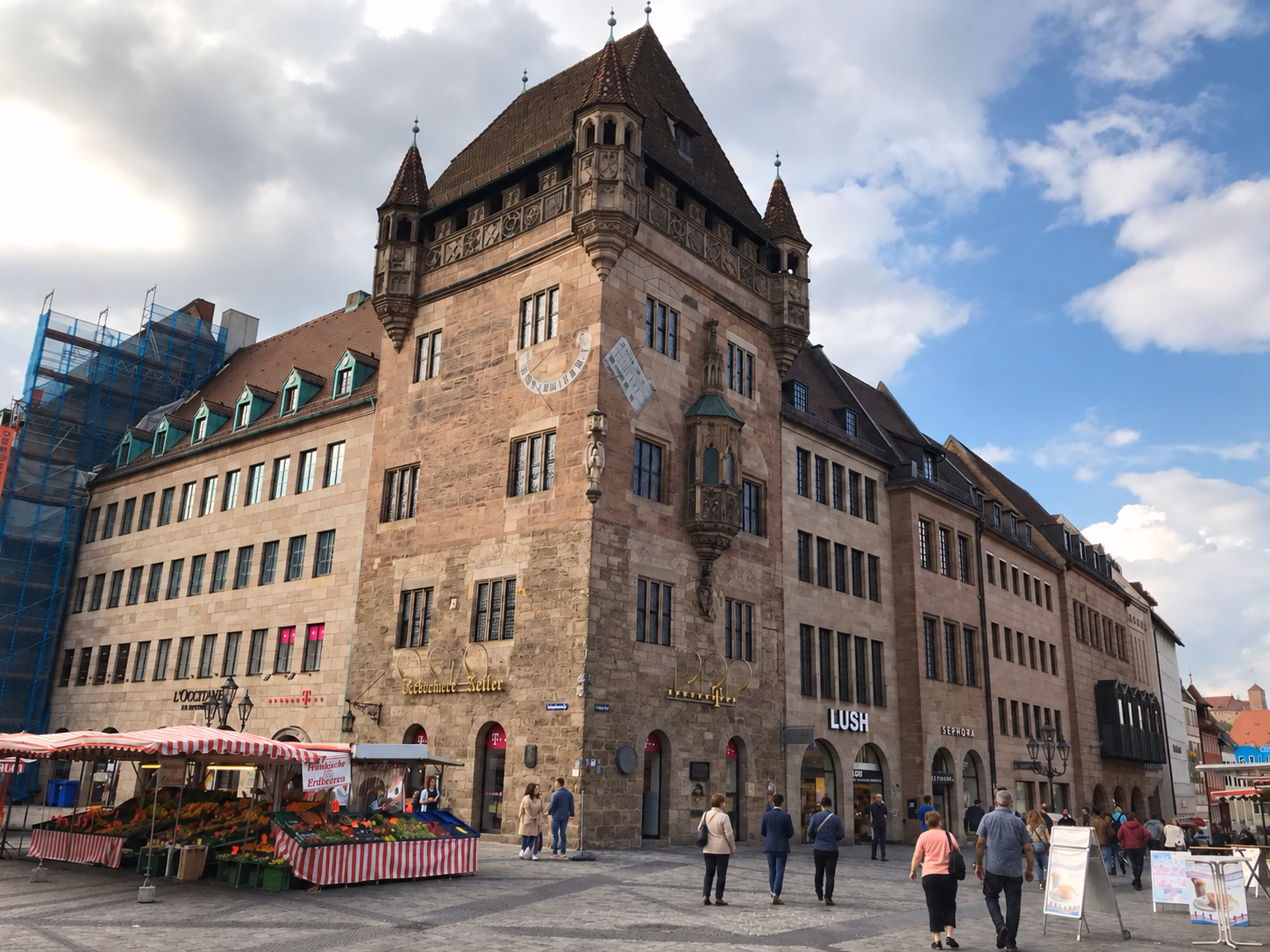 Pedestrians and flower stalls beside the historic Nassauer Haus in Nuremberg’s Old Town.