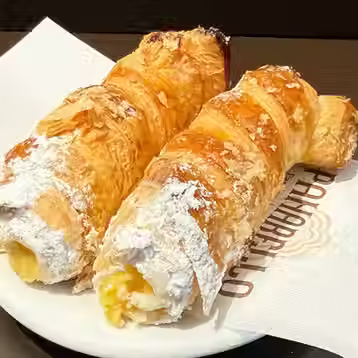 Two golden cream-filled pastries dusted with powdered sugar