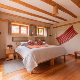 Luxury private bedroom retreat accommodation with window streaming in and hardwood floors at Munay Sonqo retreat center in Peru's Sacred Valley
