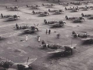 Black and white old photo of many Spitfire planes in an airfield.