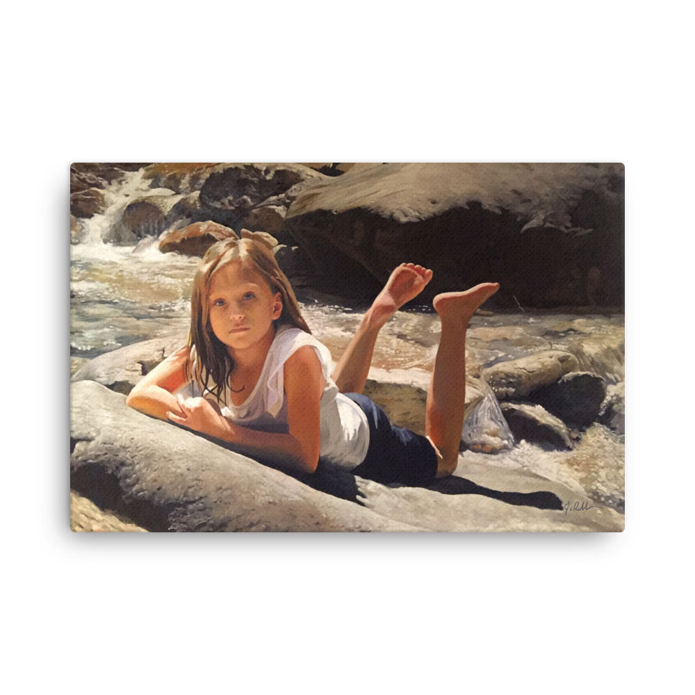 Young girl lies on river rock, water flowing in background.