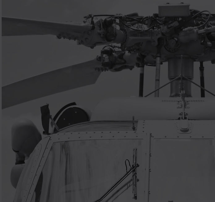 Dark grayscale image of helicopter and ground crew during evening operations