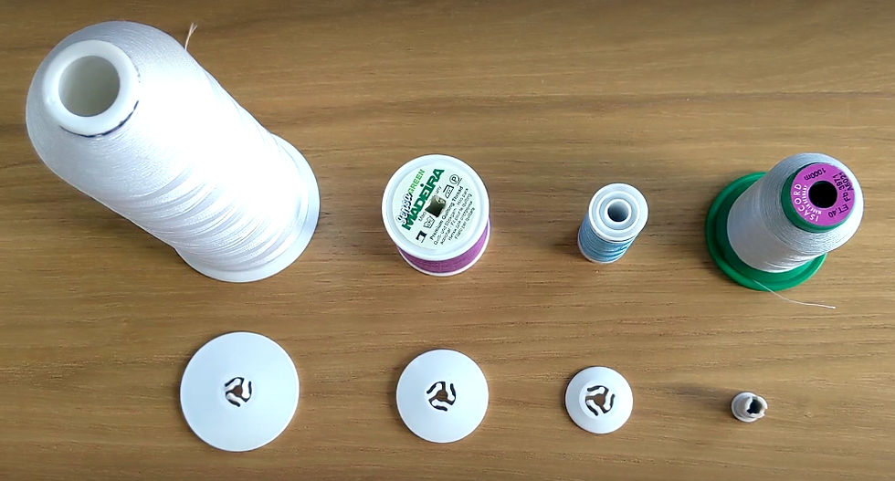 Spools of thread in various sizes, with spool caps in front, arranged neatly in a row showing the different sizes of spool need different sizes of spool cap.