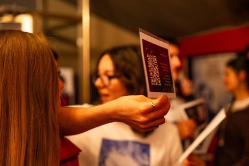 Volunteers holding a printout with an audience award votig information and QR code and inviting patrons to participate – scan the code and rate the films they watch at Cyprus Film Days International Film Festival. 
