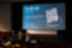 Three filmmakers take the stage at Monstra Festival for Q&A session, on the backgroung is the festival branded visual