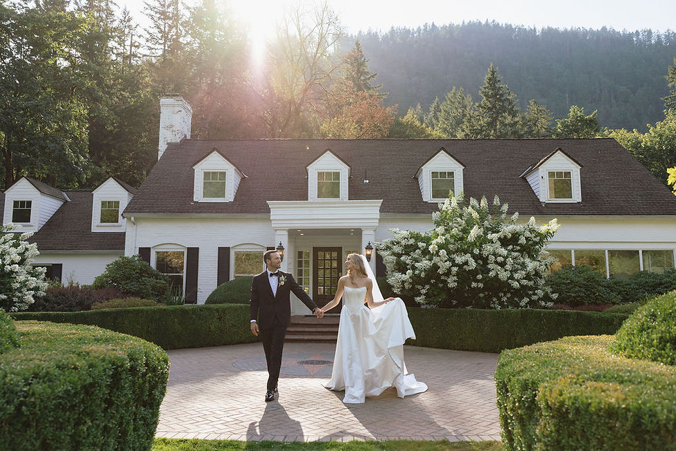 Bride and groom holding hands in front of Fox Hollow Farm during their garden wedding, lovingly gazing at each other as the bride gently holds her dress in a romantic black-tie celebration.