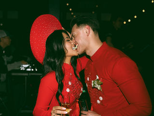 Bride and groom wearing traditional red Vietnamese áo dài sharing a celebratory moment during a black-tie wedding reception at Court in the Square in downtown Seattle