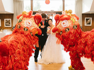Chinese and Western fusion wedding at Timberline Lodge with the couple posing alongside vibrant lion dancers during the reception