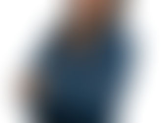 Confident woman smiling with arms crossed, wearing a dark blue blouse and gold watch, photographed against a plain white background