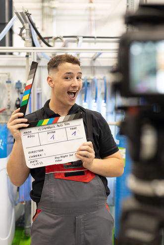Ein Azubi von Grenzebach hat eine Filmklappe in der Hand 