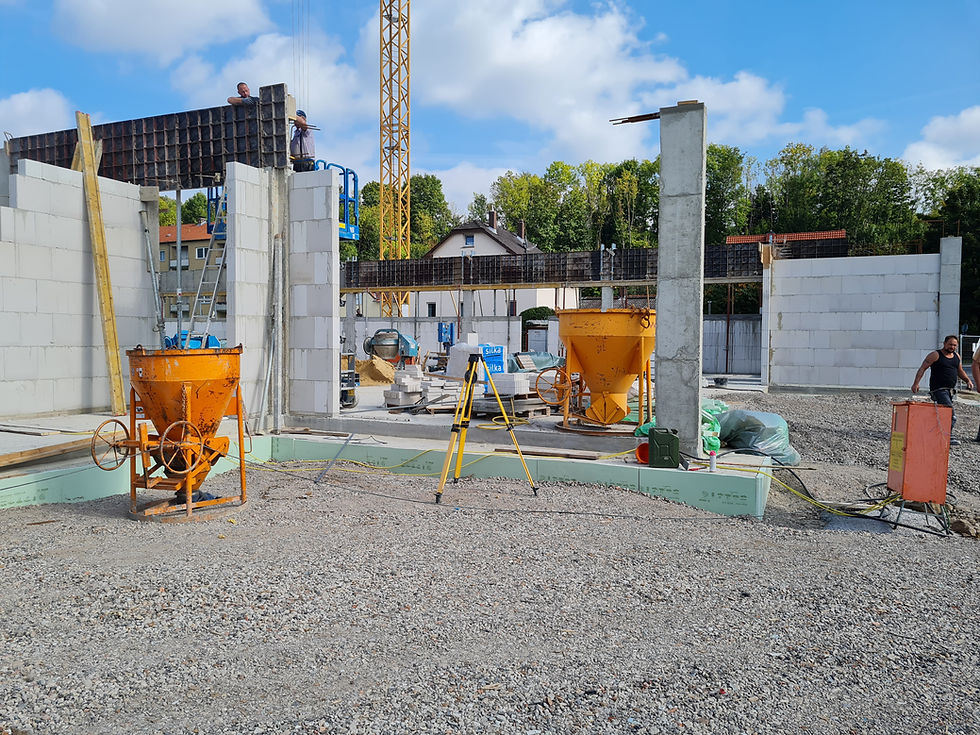 Baustelle der Firma Barteg mit Betonmischern und einem großen Kran im Einsatz. Arbeiter in Sicherheitsausrüstung sind aktiv.