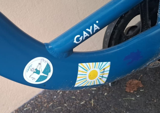 Vélo bleu avec logos GAYA, soleil, et autres symboles sur le cadre.