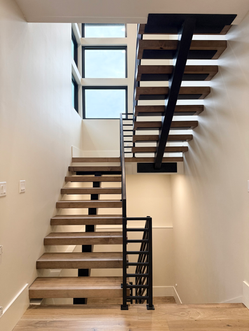 Floating staircase with solid maple treads and sleek black railing by Iron Timbers, built for precision and competitive value.