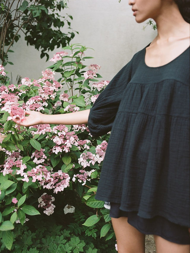 femme dans un jardin fleuri portant une tunique noire teintée Anaak
