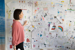 Kinderpsychologin vor einer Wand voller Kinderbilder