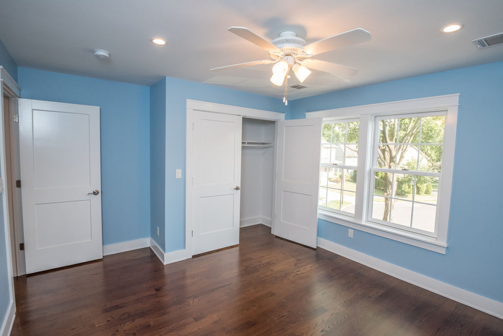 Empty blue room with wooden floor and ceiling fan.
