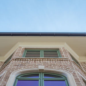 Brick house facade with green-framed windows.