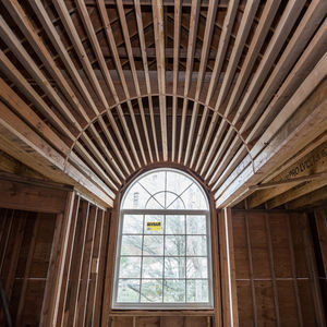 Arched window with radiating wooden beams above.