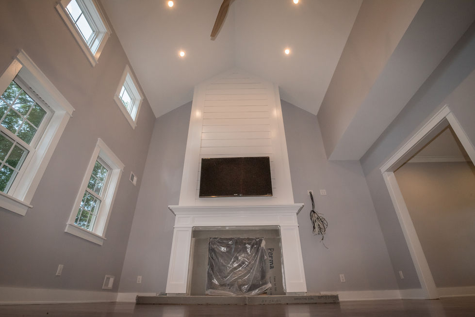 Spacious living room with high ceiling and fireplace.