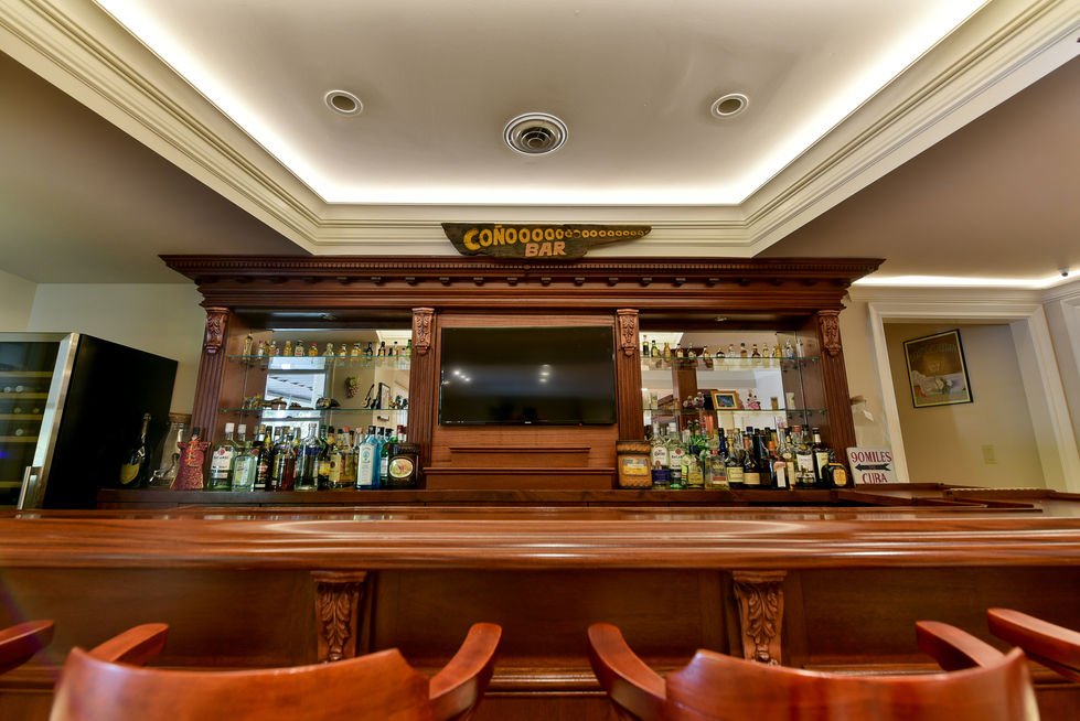 Elegant wooden bar with bottles and a TV.