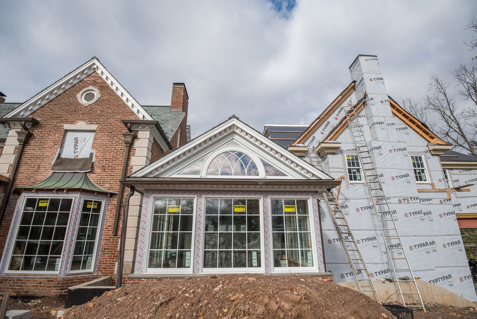 House under construction with large windows and brickwork.