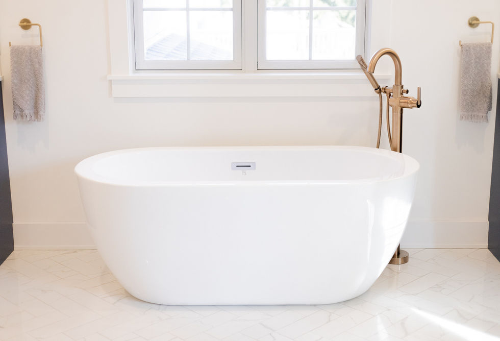 White freestanding bathtub with gold faucet.