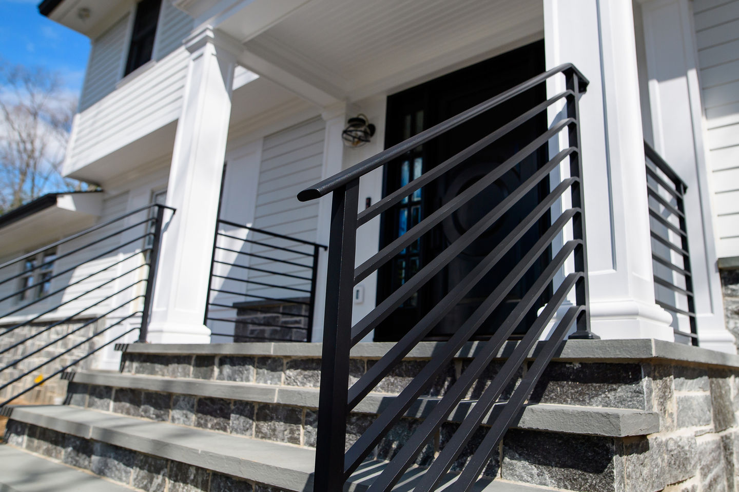 Modern black metal railing on stone steps.