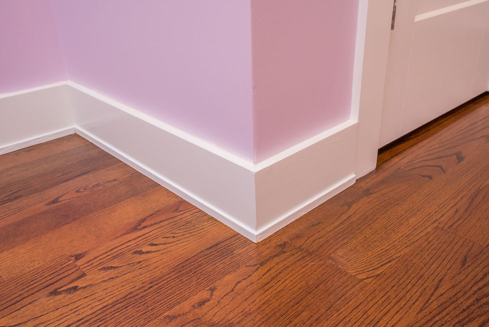 Pink wall corner with white trim and wooden floor.